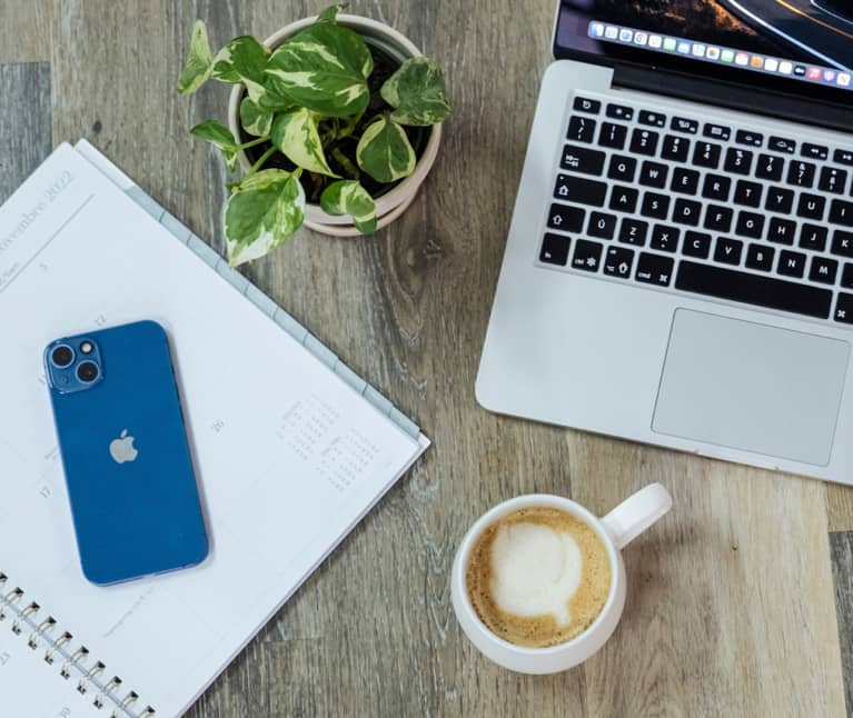 photo aesthétique d'un portable, un cahier, une plante et un café sur une surface en bois